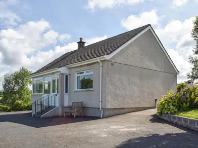 a small house with a bench in front of it at Lilybank Cottage in Doularg