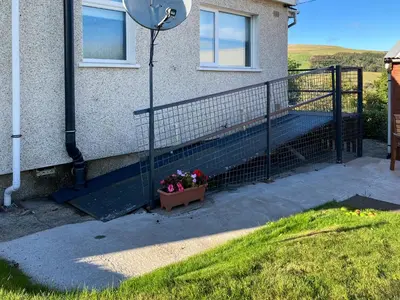 a house with a fence and a pot of flowers at Lilybank Cottage in Doularg