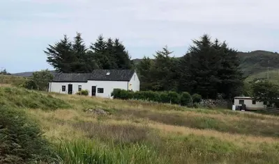 a white house on a hill in a field at Cottage-IsleofMull-StunningViews-WiFi-Parking in Bunessan