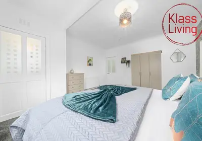 a bedroom with a bed with a green blanket on it at Fraser House by Klass Living Rutherglen in Glasgow
