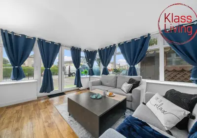 a living room with blue curtains and a table at Fraser House by Klass Living Rutherglen in Glasgow