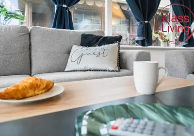 a coffee table with a plate of croissants and a coffee cup at Fraser House by Klass Living Rutherglen in Glasgow