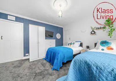 two beds in a bedroom with blue walls at Fraser House by Klass Living Rutherglen in Glasgow