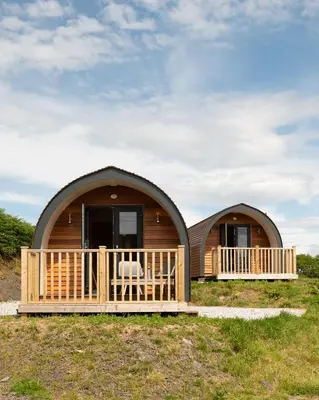 a log cabin with a porch and a deck at Countryside Farm Pod on Isle of Seil - A in Balvicar
