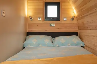 a small bed in a small room with a window at Countryside Farm Pod on Isle of Seil - A in Balvicar