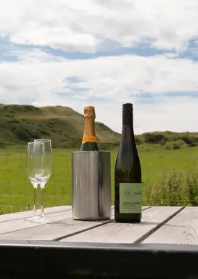 a bottle of wine and a glass on a table at Countryside Farm Pod on Isle of Seil - A in Balvicar