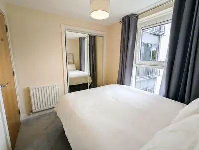 a bedroom with a white bed and a large window at Parkgate 2 bed, private parking, Rosyth M90 in Rosyth