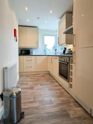a kitchen with white cabinets and a trash can at Parkgate 2 bed, private parking, Rosyth M90 in Rosyth