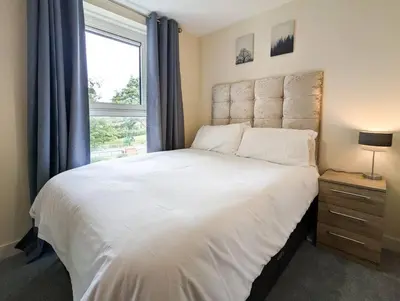 a bedroom with a large white bed with a window at Parkgate 2 bed, private parking, Rosyth M90 in Rosyth