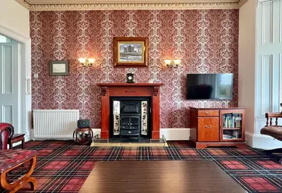 a living room with a fireplace and a tv at St Abbs in Innellan