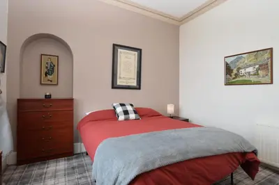 a bedroom with a red bed and a dresser at St Abbs in Innellan