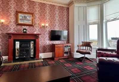 a living room with a fireplace and a television at St Abbs in Innellan