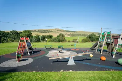 a park with a playground with swings and a slide at Cottage with Hot Tub near Knockhill in Saline