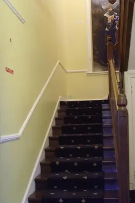 a hallway with a staircase with a woman in a painting at Twin Lions Hotel in Edinburgh