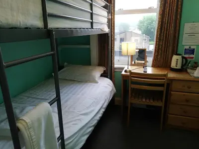 a bedroom with a bunk bed and a desk and a window at Twin Lions Hotel in Edinburgh