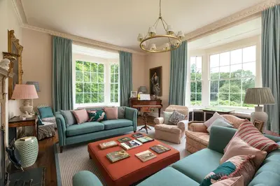 a living room with blue furniture and windows at Dabton House in Carronbridge