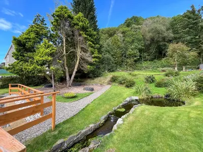 a garden with a wooden bench and a pond at Oak -Apartment 4 in Aberfoyle