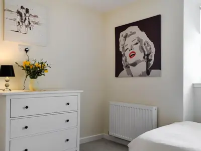 a bedroom with a dresser and a painting on the wall at Oak -Apartment 4 in Aberfoyle