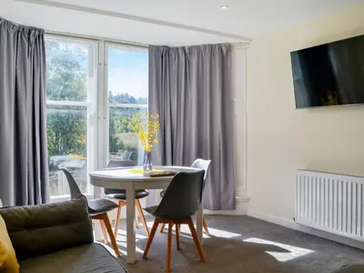 a living room with a table and chairs and a window at Oak -Apartment 4 in Aberfoyle