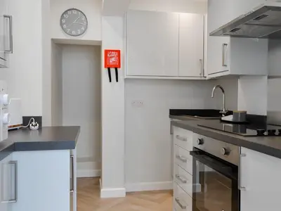 a kitchen with white cabinets and a clock on the wall at Oak -Apartment 4 in Aberfoyle