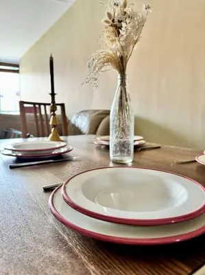 a table with plates and a vase with flowers in it at Two bedroom maisonette in the heart of the West End in Glasgow