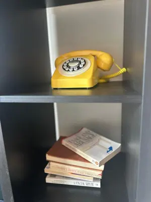 a yellow phone sitting on a shelf with books at Colourful life-house near Glasgow in Clydebank