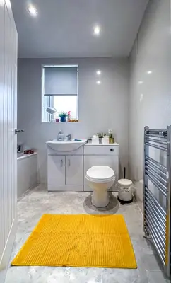 a bathroom with a white toilet and a yellow rug at Colourful life-house near Glasgow in Clydebank