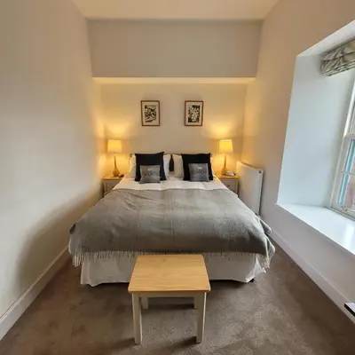 a bedroom with a large bed and two lamps at Loch Lomond Finnich Cottages in Drymen