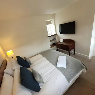 a bedroom with a large bed and a television at Loch Lomond Finnich Cottages in Drymen
