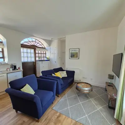 a living room with two blue couches and a tv at Loch Lomond Finnich Cottages in Drymen