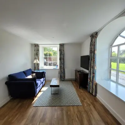 a living room with a couch and a tv at Loch Lomond Finnich Cottages in Drymen