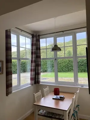 a dining room with a table and a large window at Siskin Cottage in Lochgilphead