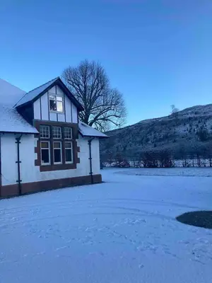 a house with snow on the ground next to a field at Siskin Cottage in Lochgilphead