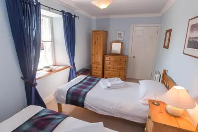 a bedroom with two beds and a window at Ballat Smithy Cottage in Drymen