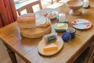 a wooden table with bread and eggs and cheese on it at Ballat Smithy Cottage in Drymen