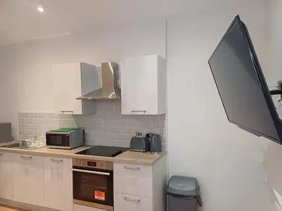 a kitchen with a stove and a tv on a wall at The Hazlitt Apartments in Paisley