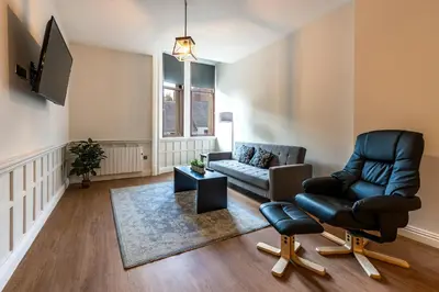 a living room with a couch and a chair at The Hazlitt Apartments in Paisley