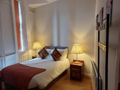 a bedroom with a bed with two lamps on a table at The Hazlitt Apartments in Paisley