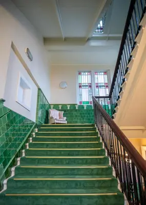 a staircase in a building with green tiles at The Hazlitt Apartments in Paisley