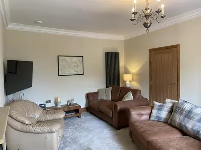 a living room with a couch and a chair at 1 Inveravon Cottage in Falkirk