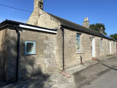 an old stone building with a gate on a street at 1 Inveravon Cottage in Falkirk