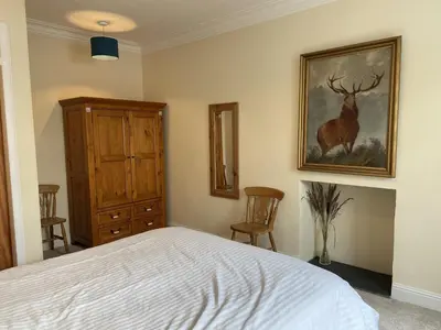 a bedroom with a bed and a painting of a deer at 1 Inveravon Cottage in Falkirk