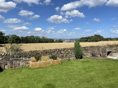 a stone wall with a flower bed in the grass at 1 Inveravon Cottage in Falkirk