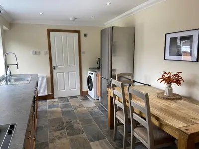 a kitchen with a wooden table and chairs in a kitchen at 1 Inveravon Cottage in Falkirk