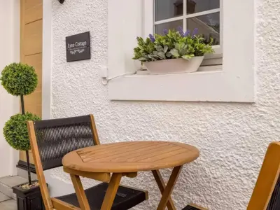 a wooden table and chair sitting in front of a window at Lyne Cottage, The Retreat in West Linton