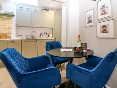 a kitchen with blue chairs and a table with a bottle of wine at Lyne Cottage, The Retreat in West Linton