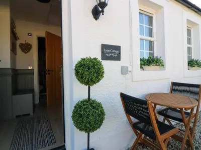 a table and two chairs in front of a house at Lyne Cottage, The Retreat in West Linton