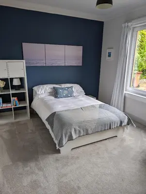 a bedroom with a bed with a blue wall at Beautiful double room B&B great location homeshare Edinburgh in Edinburgh