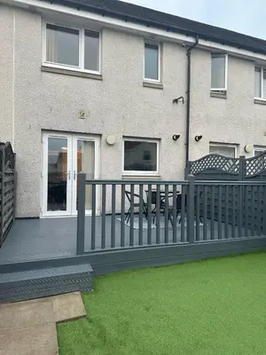a house with a wooden deck with a fence at Black Daisy in Glasgow