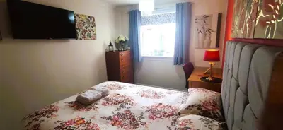 a bedroom with a bed with a flowered blanket and a television at Double room in riverside apartment in Glasgow